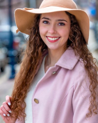 Person with white teeth in a hat and pink outfit