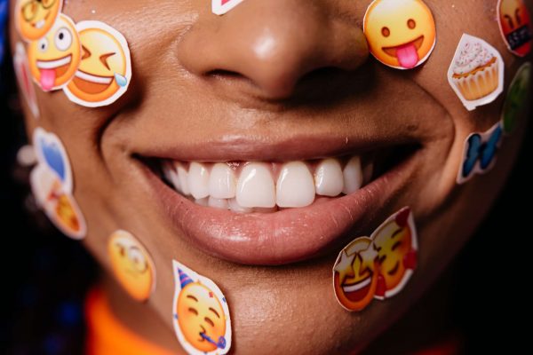 Person smiling with white teeth and a few stickers all over the face